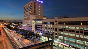 Un hotel de varios pisos con un llamativo letrero 'PEARL VIEW', rodeado de calles urbanas y otros edificios.