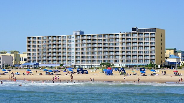 Een hotel aan het strand met meerdere balkons en een zandstrand.