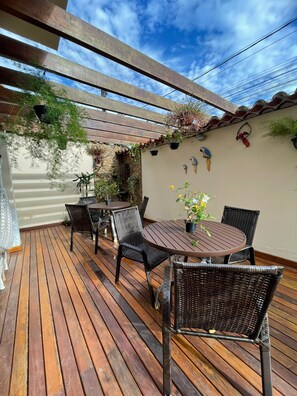 An outdoor patio with wooden flooring, wicker furniture, and potted plants. - Pousada Alecrim Dourado (Paraty)