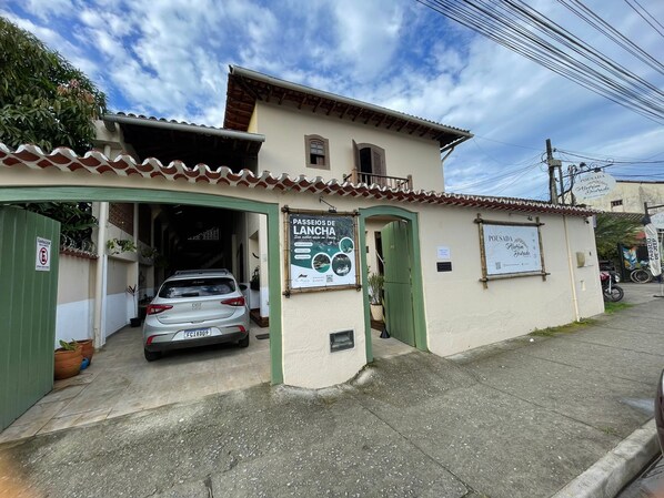 A building with a sign advertising 'Passeios de Lanchada' and a parked car. - Pousada Alecrim Dourado (Paraty)