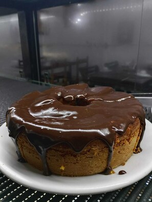 A chocolate-glazed bundt cake on a white plate. - Pousada Alecrim Dourado (Paraty)
