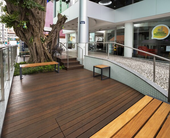 Un espacio interior moderno con suelo de madera, un árbol grande y bancos.