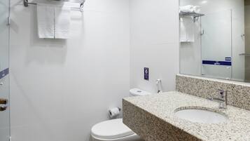 A modern bathroom with a granite countertop, white fixtures, and a large mirror.