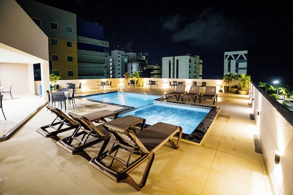 Una piscina al aire libre, sombrillas, tumbonas