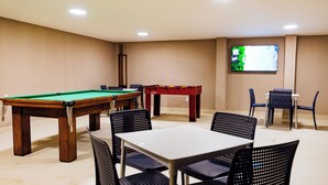 Ein Raum mit Billardtisch, Poolbillard und einem an der Wand befestigten Fernseher.