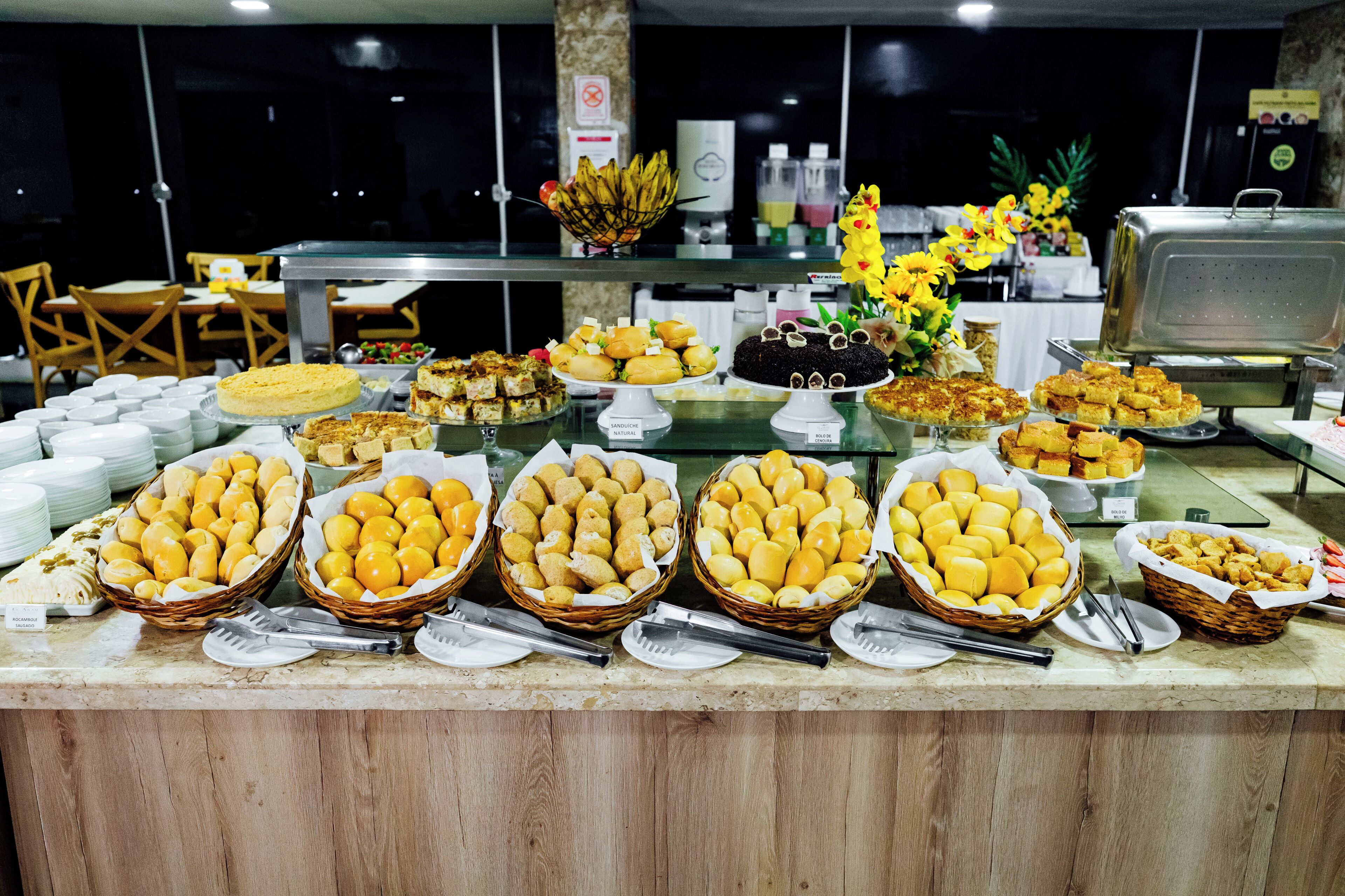 A buffet with various food items and a decorative flower arrangement.
