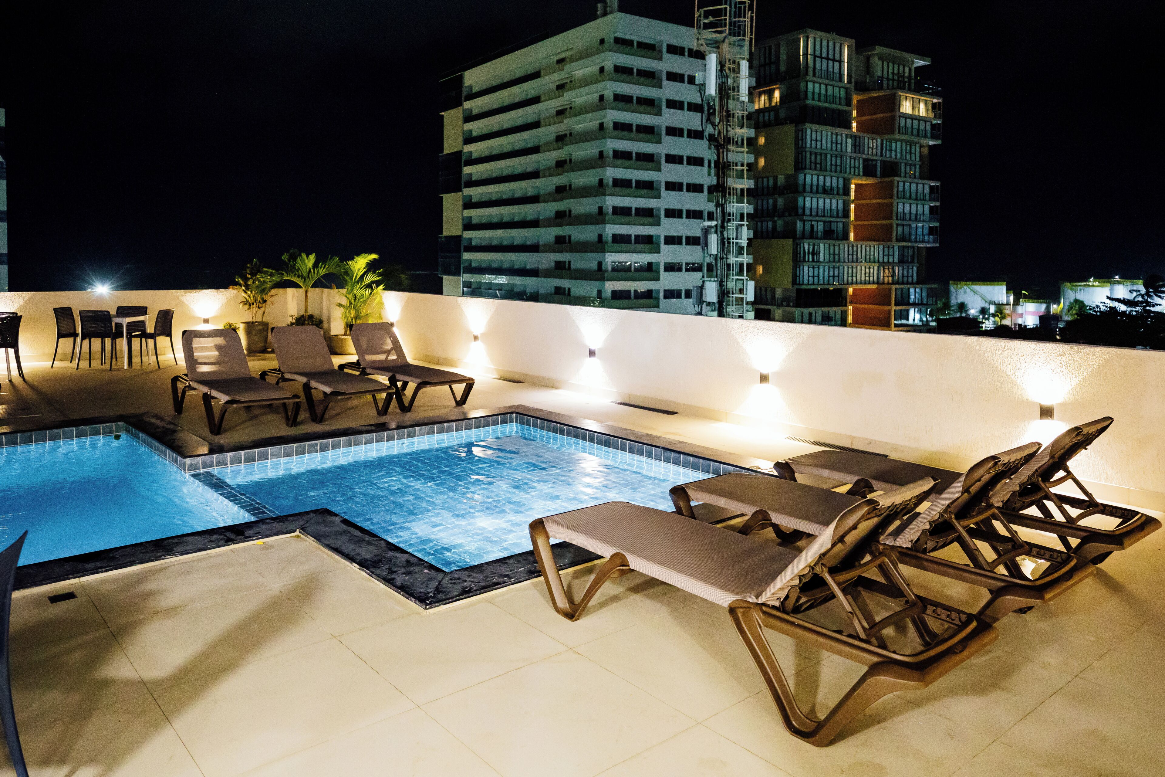 Área de piscina no terraço com espreguiçadeiras e uma piscina.