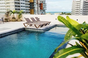 Una piscina al aire libre, sombrillas, sillones reclinables de piscina