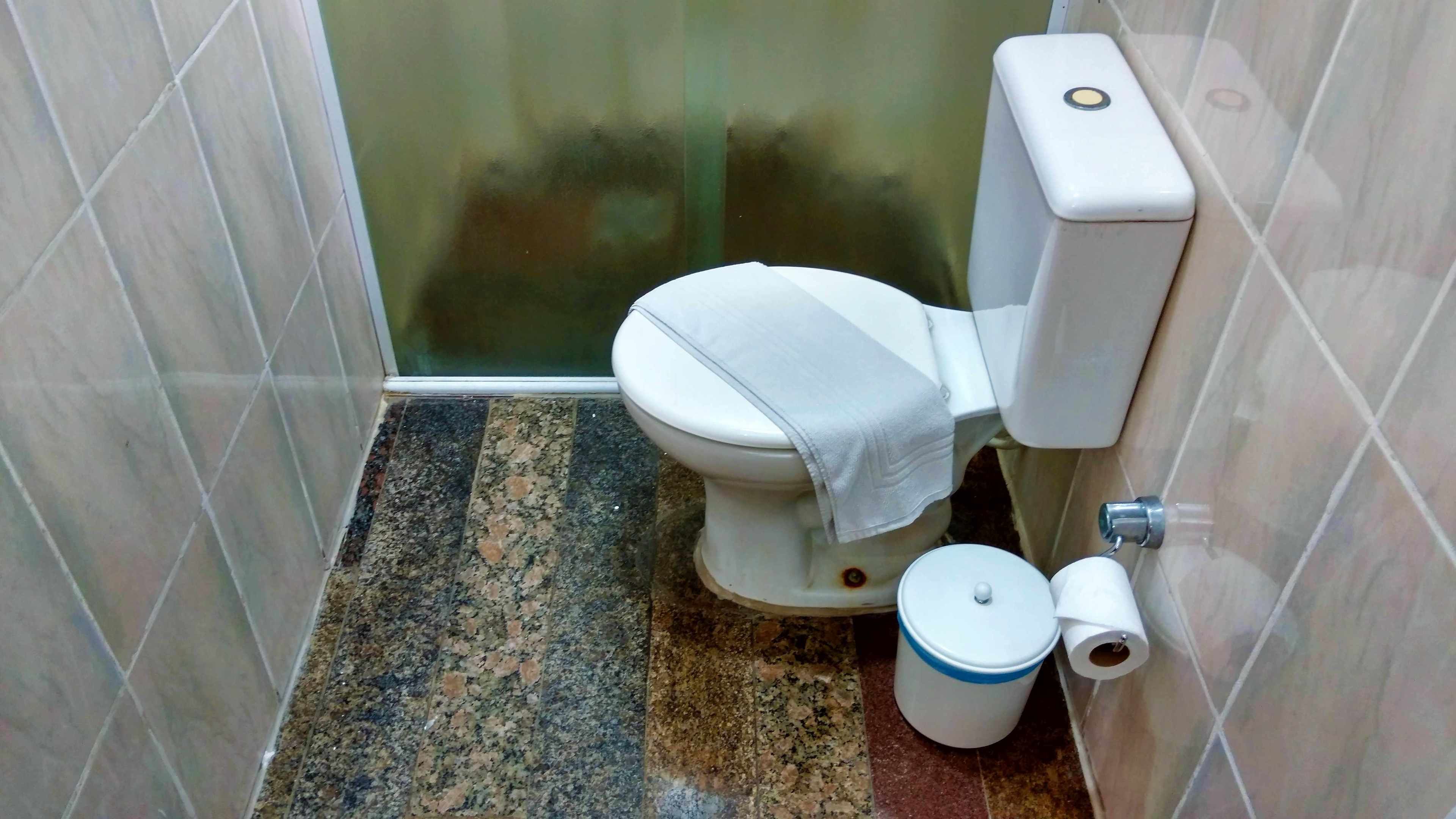 Un baño pequeño con inodoro, un cubo de basura y zona de ducha.