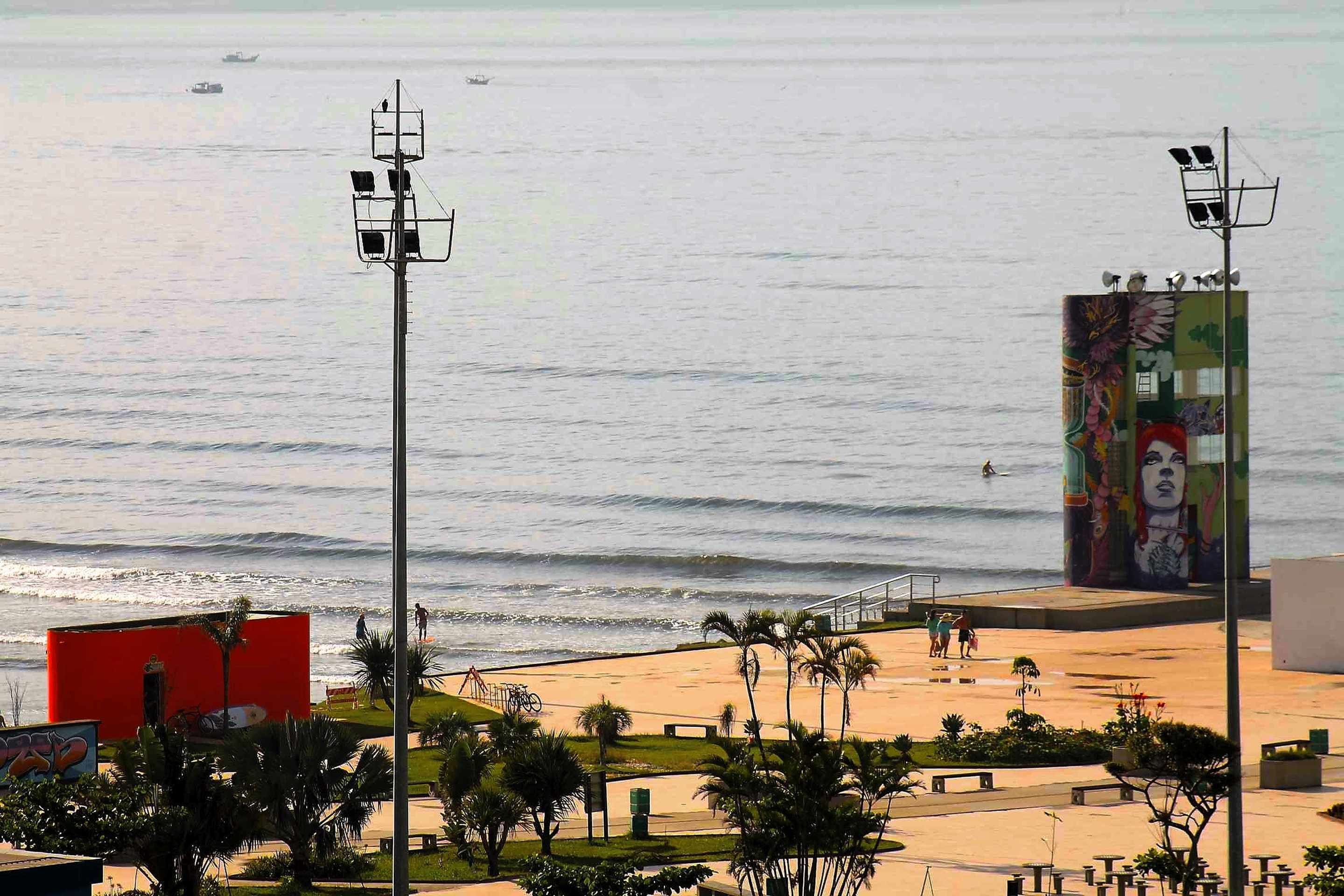 A beach with a mural, palm trees, and a red structure.