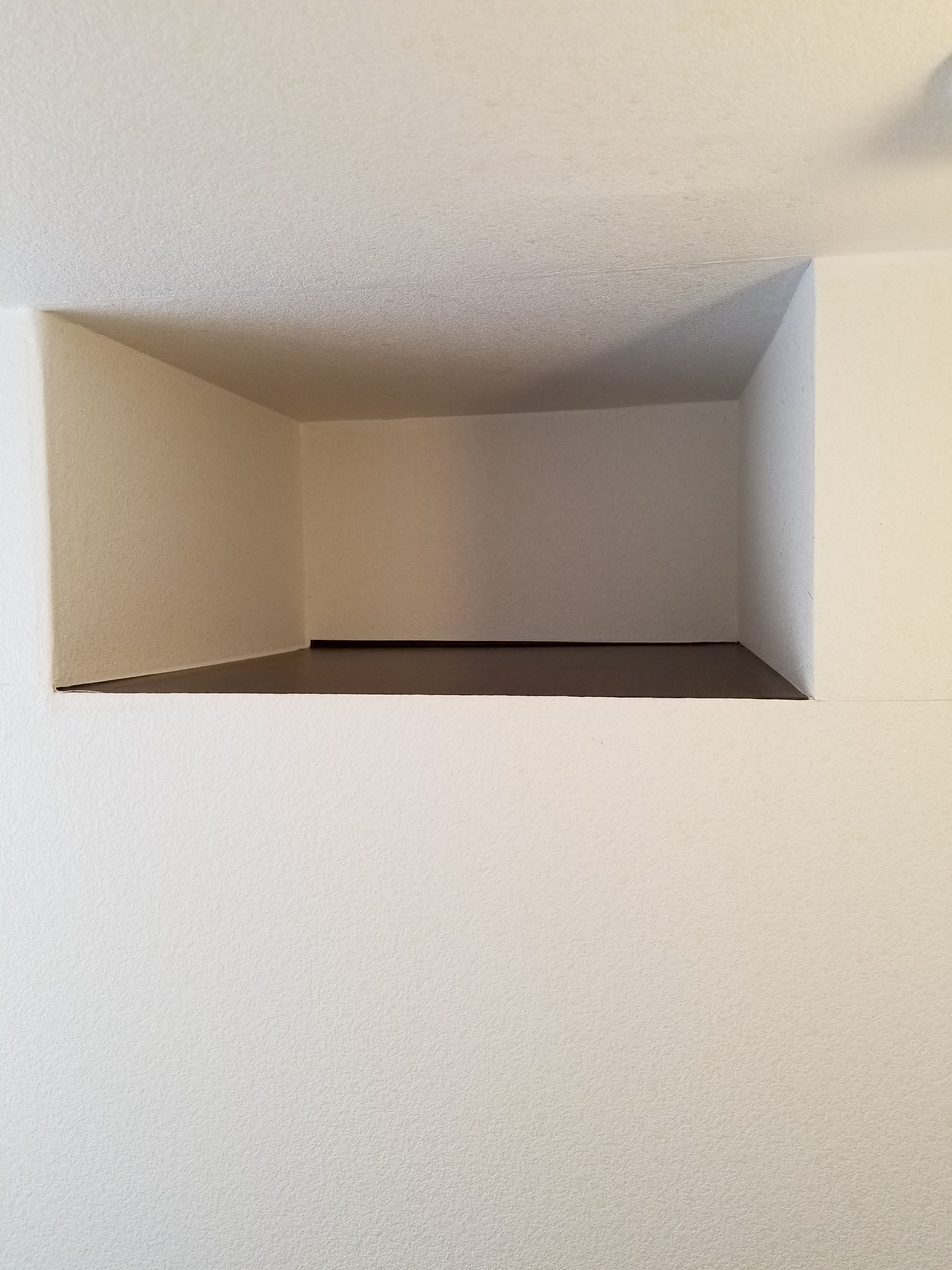 A corner of a room with white walls and a ceiling.