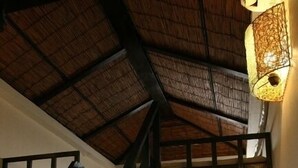 A spacious room with a wooden floor, a round table, a staircase, and a large window offering a view of the outdoors. - Lohas Villa - Hostel (Naha)