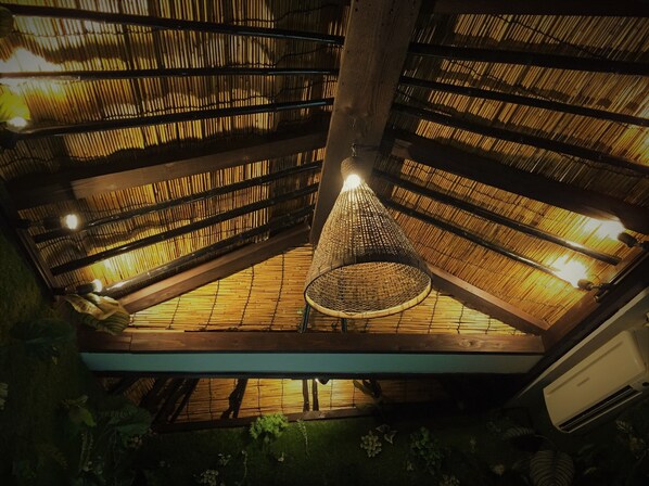 Una habitación con techo de bambú y lámpara colgante.