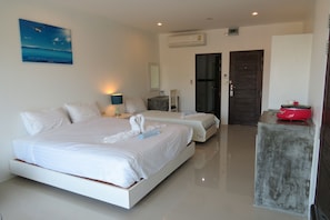 A modern hotel room with a large bed, a smaller bed, a desk, and a wardrobe.