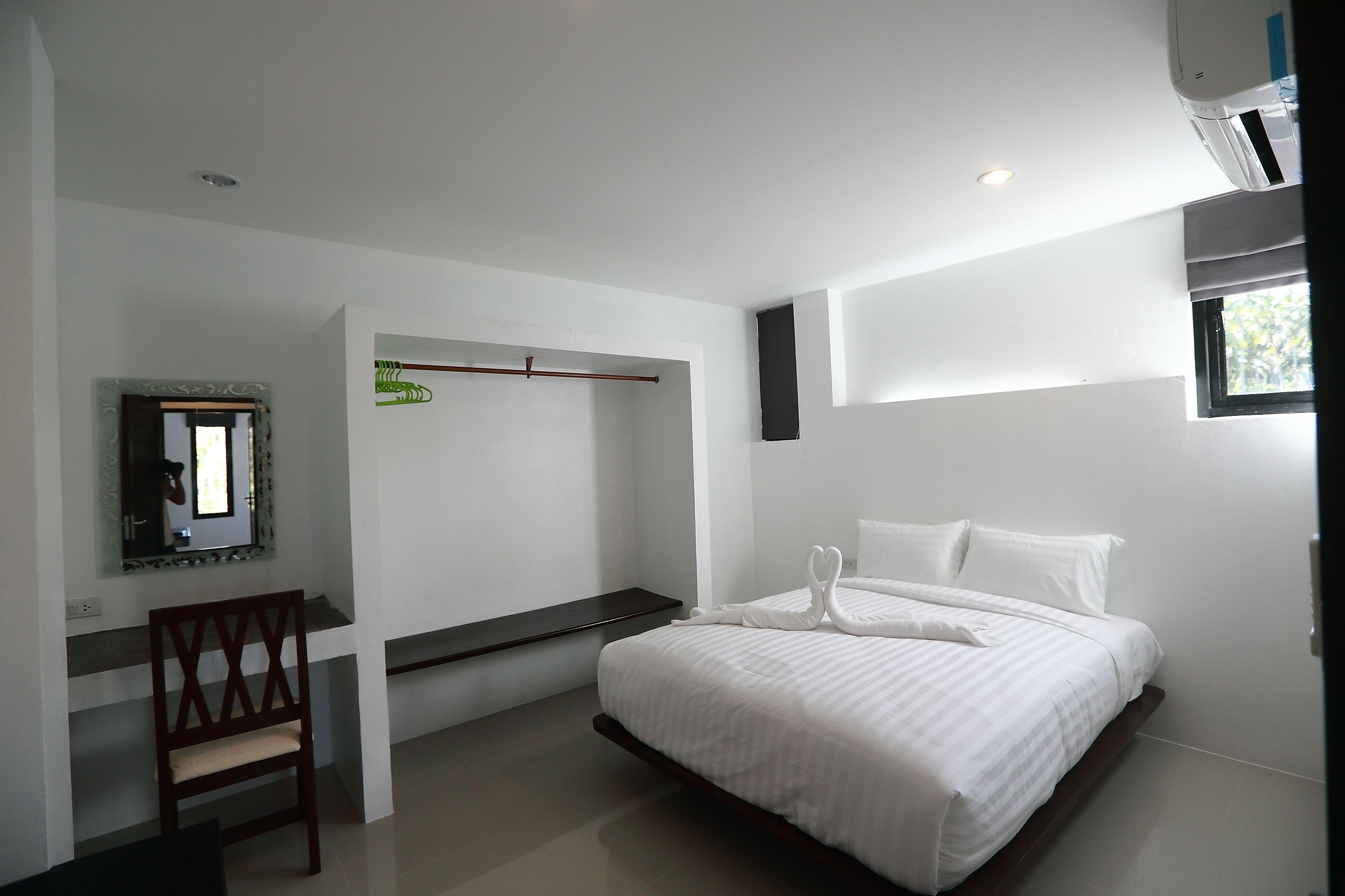 Un dormitorio moderno con una cama, una silla, un espejo y una ventana.