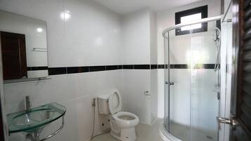 A modern bathroom with a glass sink, a toilet, and a glass-enclosed shower.