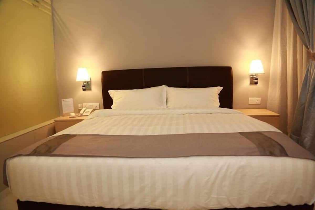 Una habitació d'hotel amb un llit gran, dues làmpades de nit, una tauleta de nit i un telèfon.