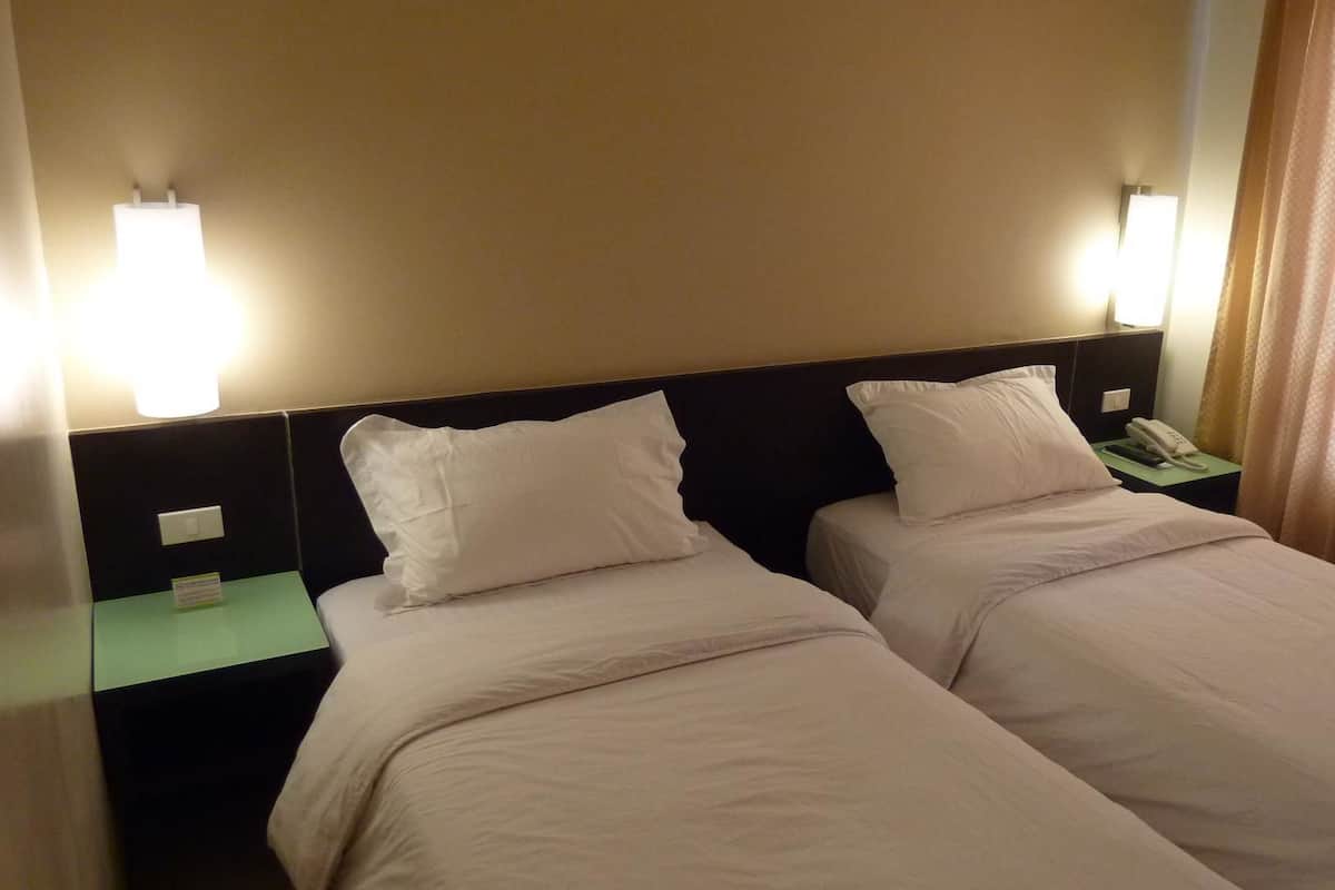 Habitació d'hotel amb dos llits individuals, una nit falda amb un telèfon i llums penjades a la paret.