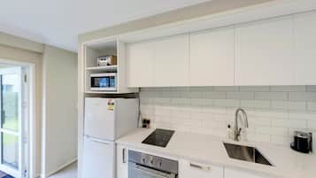 A modern kitchen with white cabinets, a built-in microwave, a refrigerator, a sink, and a stove.