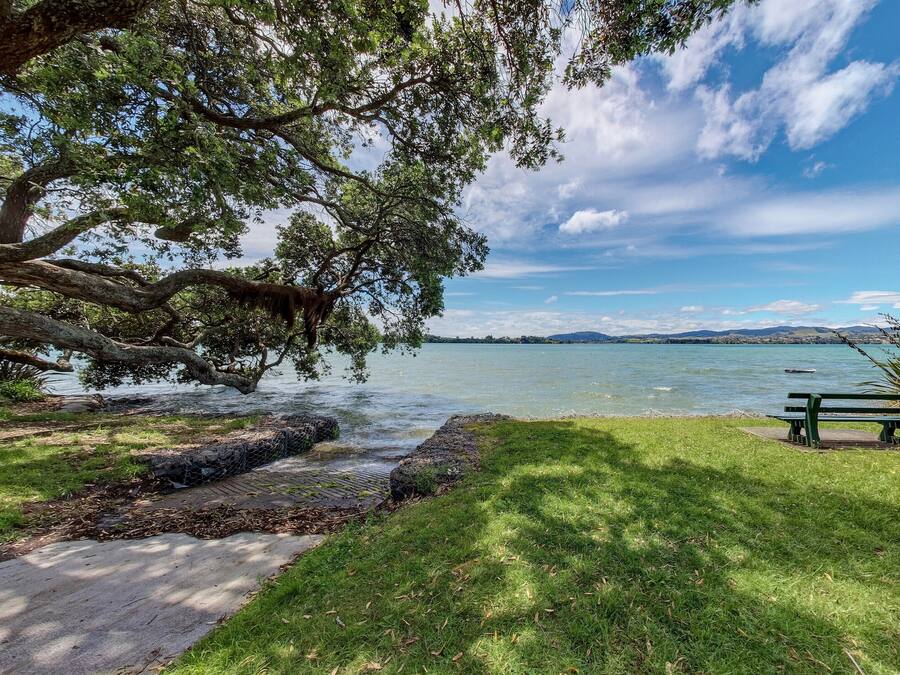 A park with a bench and a walking path by a lake.