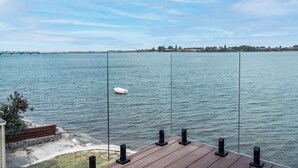 A deck with speakers and a view of a calm body of water with a boat. - Harbour View Motel and Water Front Apartments (Tauranga)