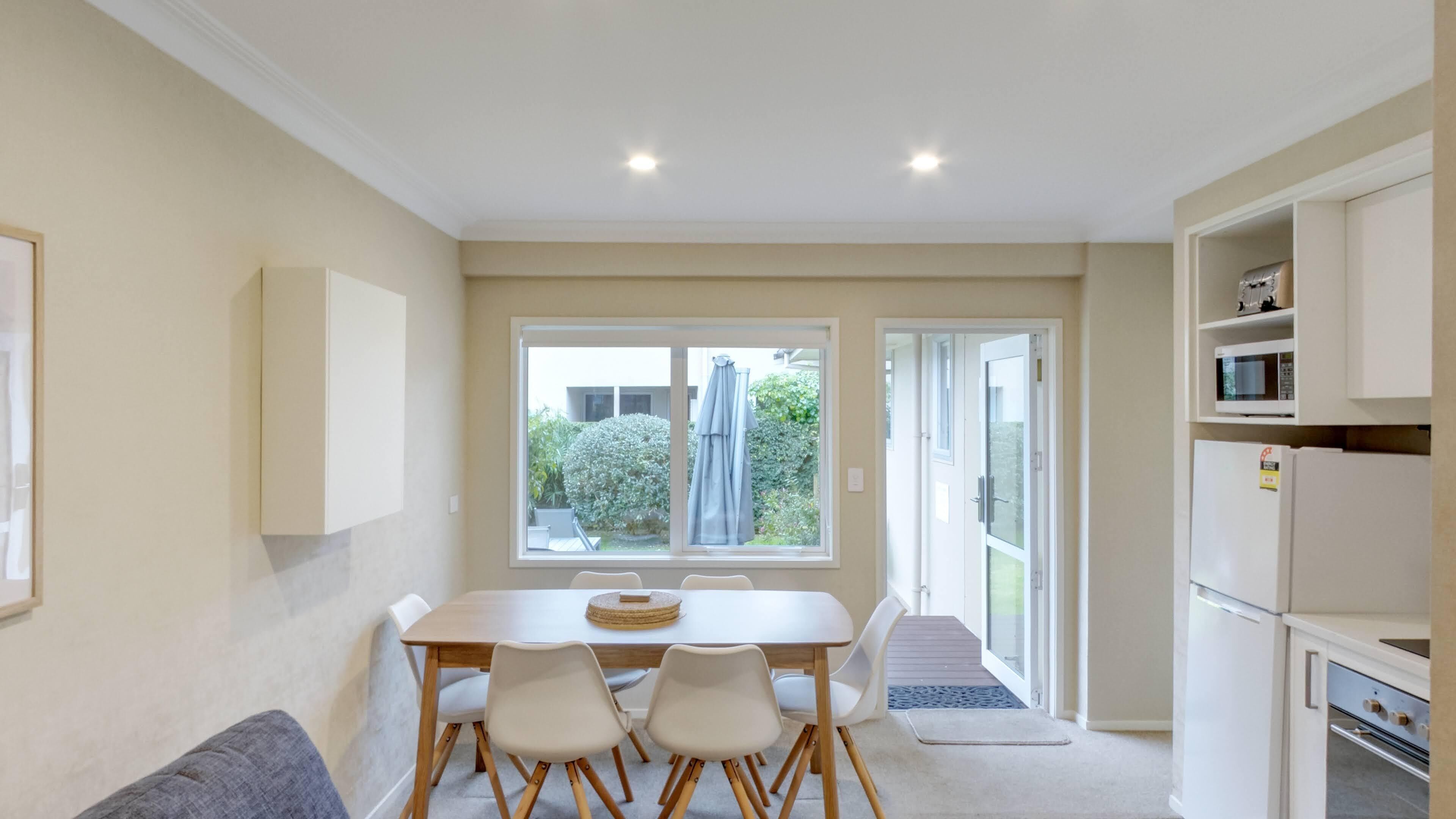 A compact kitchen with a dining area, a refrigerator, and a microwave.