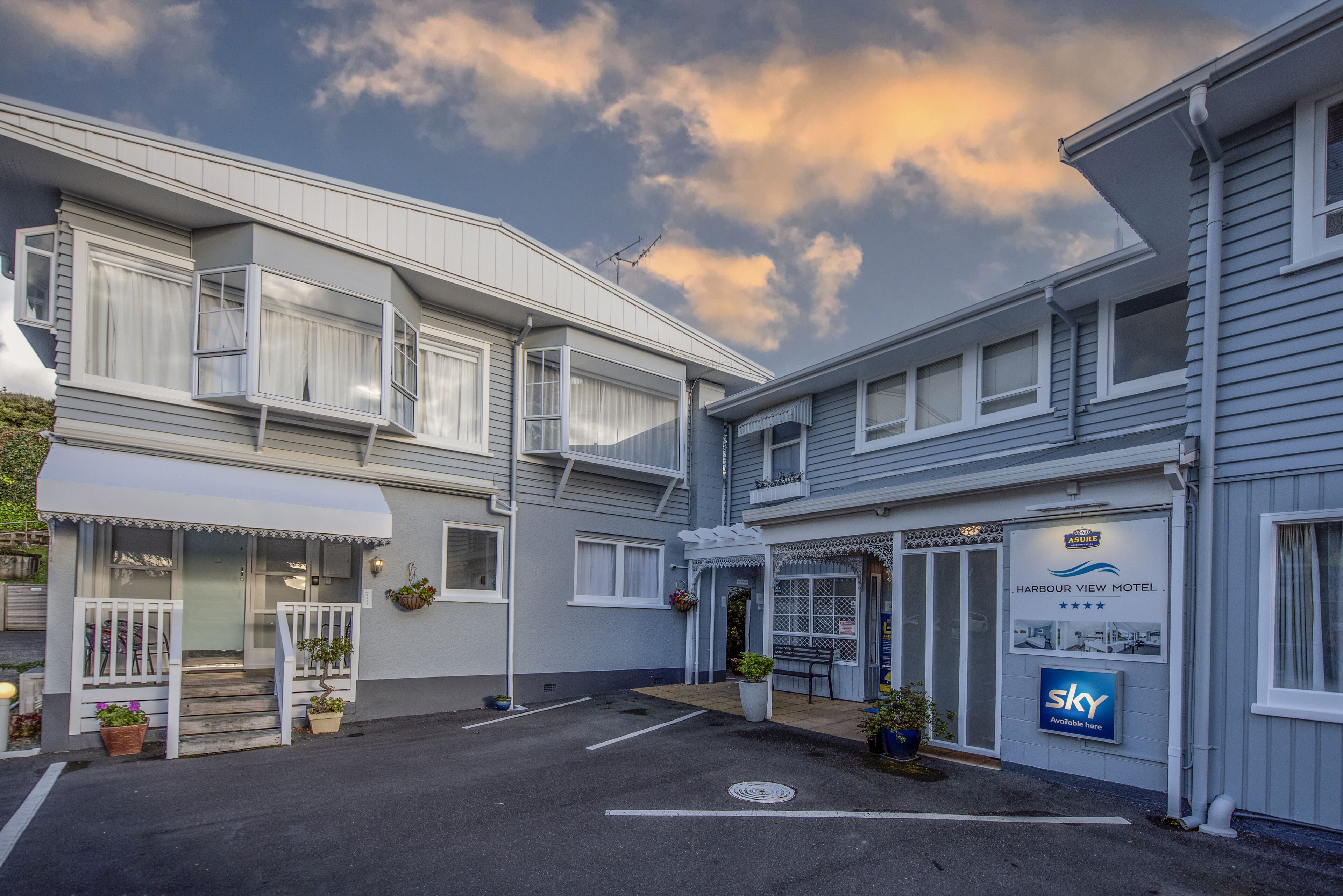 Un motel su due piani con un ingresso coperto, un parcheggio e un segnale che indica la disponibilità.