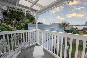 Ein Balkon mit weißer Brüstung, einer Holzbank und einem kleinen Tisch.