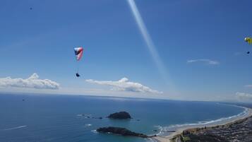 Paesaggio costiero con cielo sereno, spiaggia e un'isola all'orizzonte.