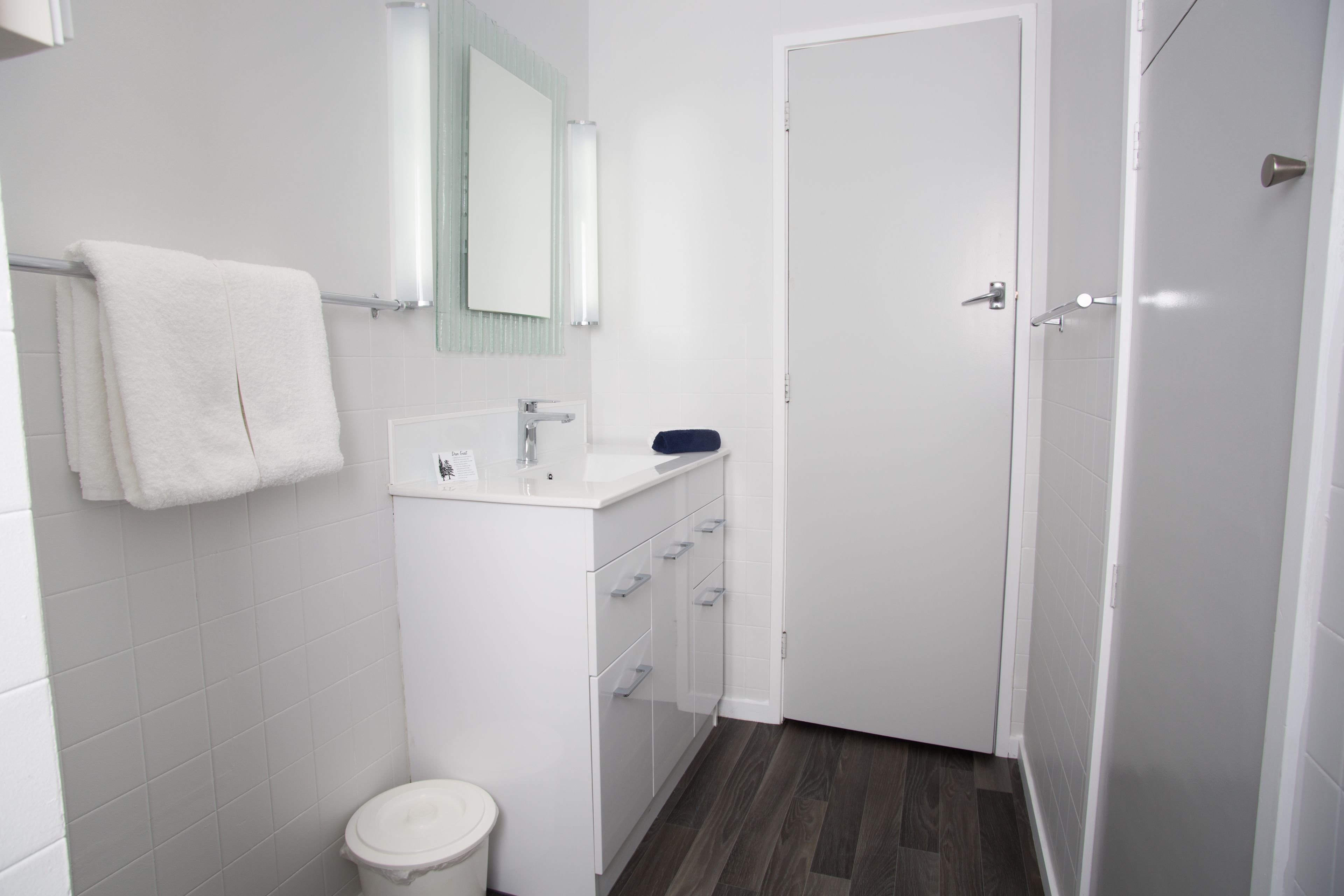 A modern bathroom with a white sink, mirror, and toilet.
