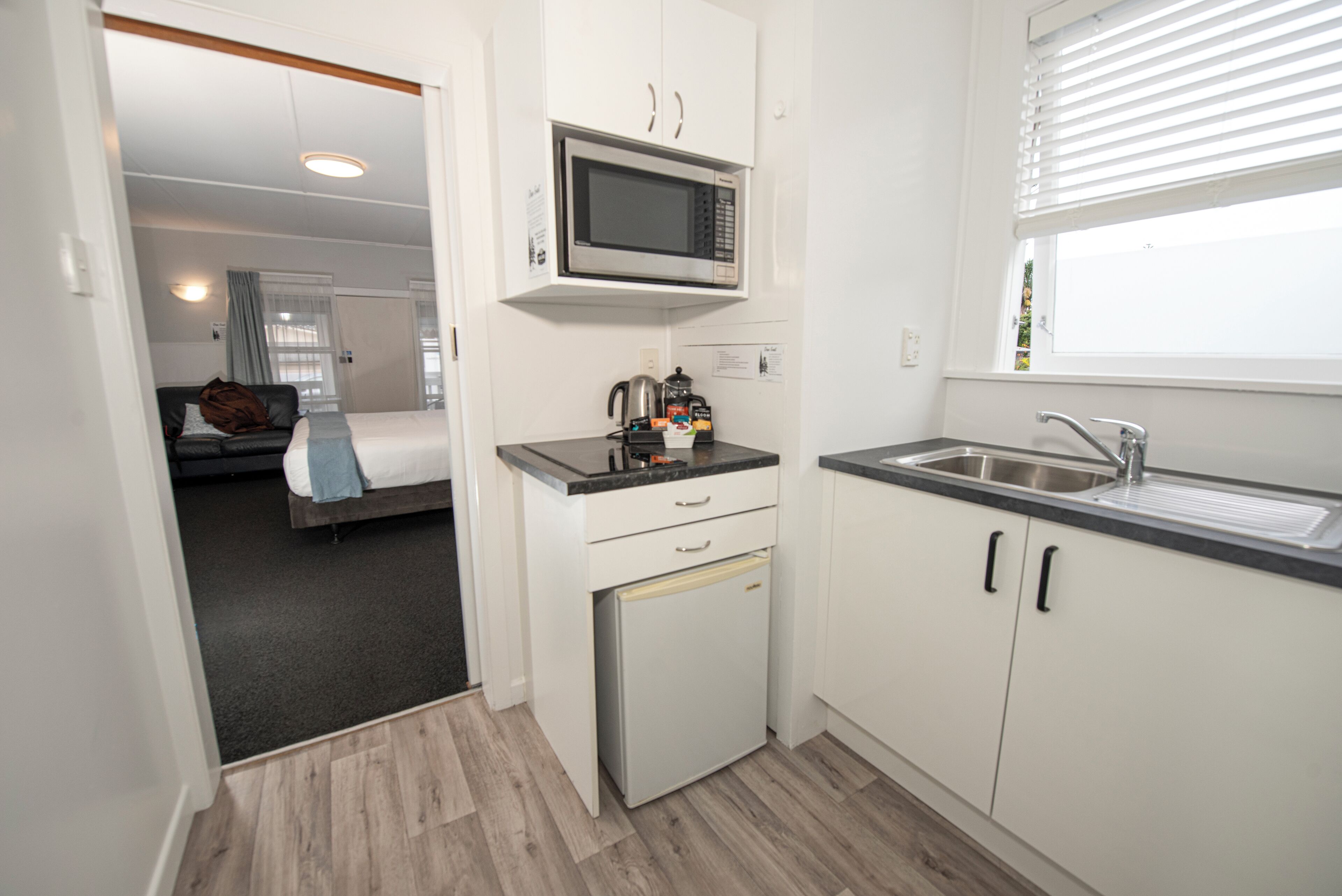 A compact kitchen with a microwave, a small refrigerator, and a sink.