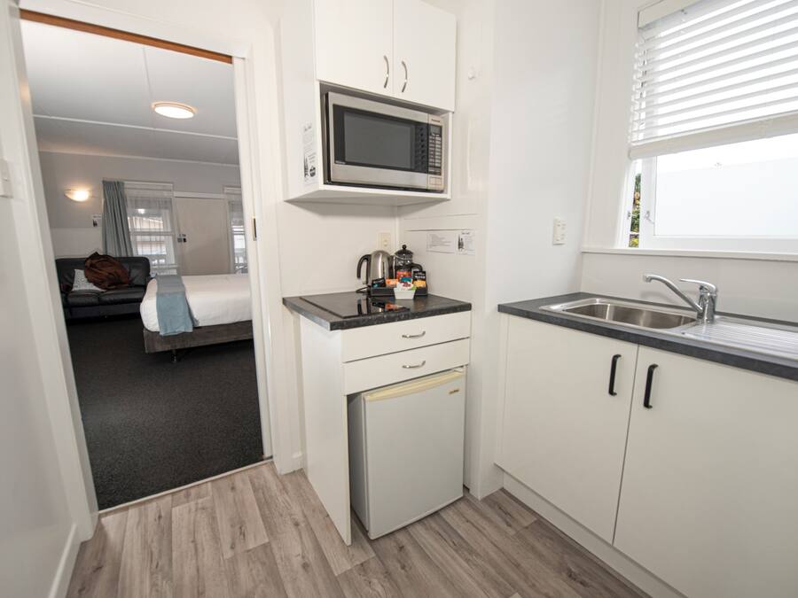 A compact kitchen with a microwave, a small refrigerator, and a sink.