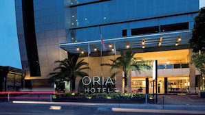 A modern hotel with a curved facade, multiple floors, and a well-lit entrance. - Oria Hotel Jakarta (Jakarta)