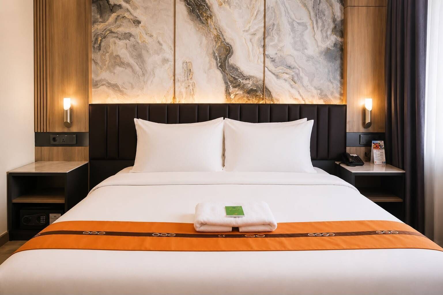 A hotel room with a bed, two bedside tables, a marble wall, and a nightstand with a lamp.