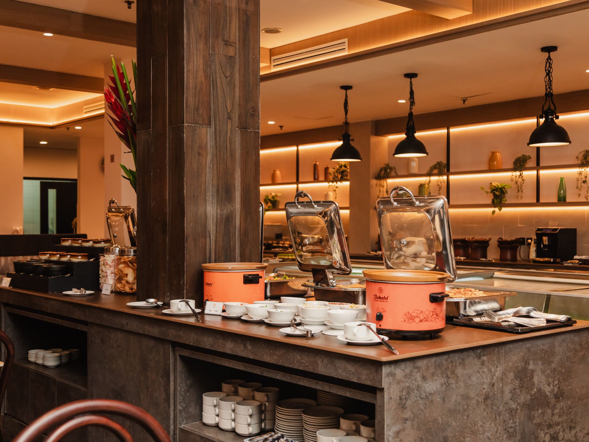 Un buffet composé de différents récipients contenant de la nourriture, d’une machine à café et d’un grand pilier central.
