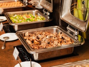A buffet with various dishes including a tray of cooked meat, a salad, and a container of vegetables. - Oria Hotel Jakarta (Jakarta)