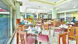 A restaurant with multiple dining tables and chairs, a buffet area, and a stage with musical instruments. - Sahid Manado (Manado)