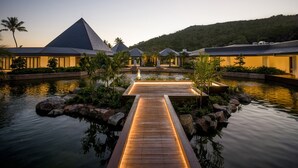 Ein Resort mit einer Holzpromenade über dem Wasser, verbunden mit mehreren Gebäuden mit Pyramiden-Dächern.