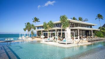 A modern resort with a pool, lounge areas, and a view of the ocean.