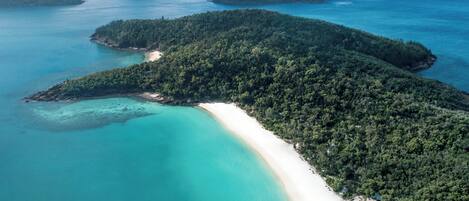 An aerial view of a tropical island with a white sandy beach and turquoise waters.