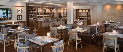 Un restaurant doté de mobilier en bois, d’un bar et de luminaires suspendus.
