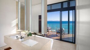 A modern bathroom with a large sink and a large mirror. There is a balcony with a view of the ocean. - InterContinental Hayman Great Barrier Reef by IHG (Whitsundays)