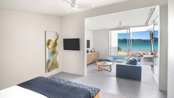 A modern bedroom with a large bed, a painting, a TV, and a balcony with a view of the sea.