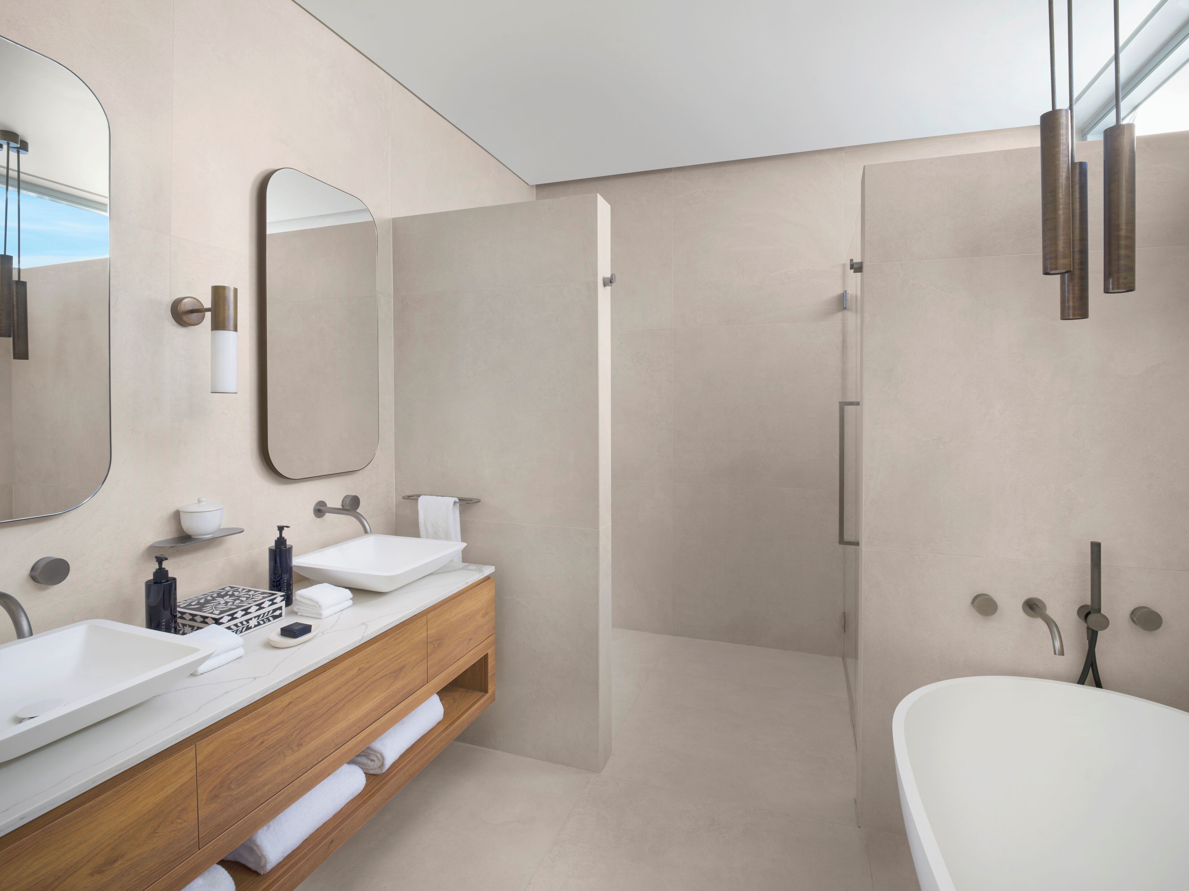 A modern bathroom with a large mirror, two sinks, a bathtub, and a shower area.