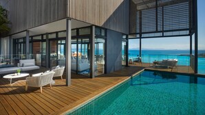 A modern outdoor pool area with a wooden deck, lounge chairs, and a view of the ocean. - InterContinental Hayman Great Barrier Reef by IHG (Whitsundays)