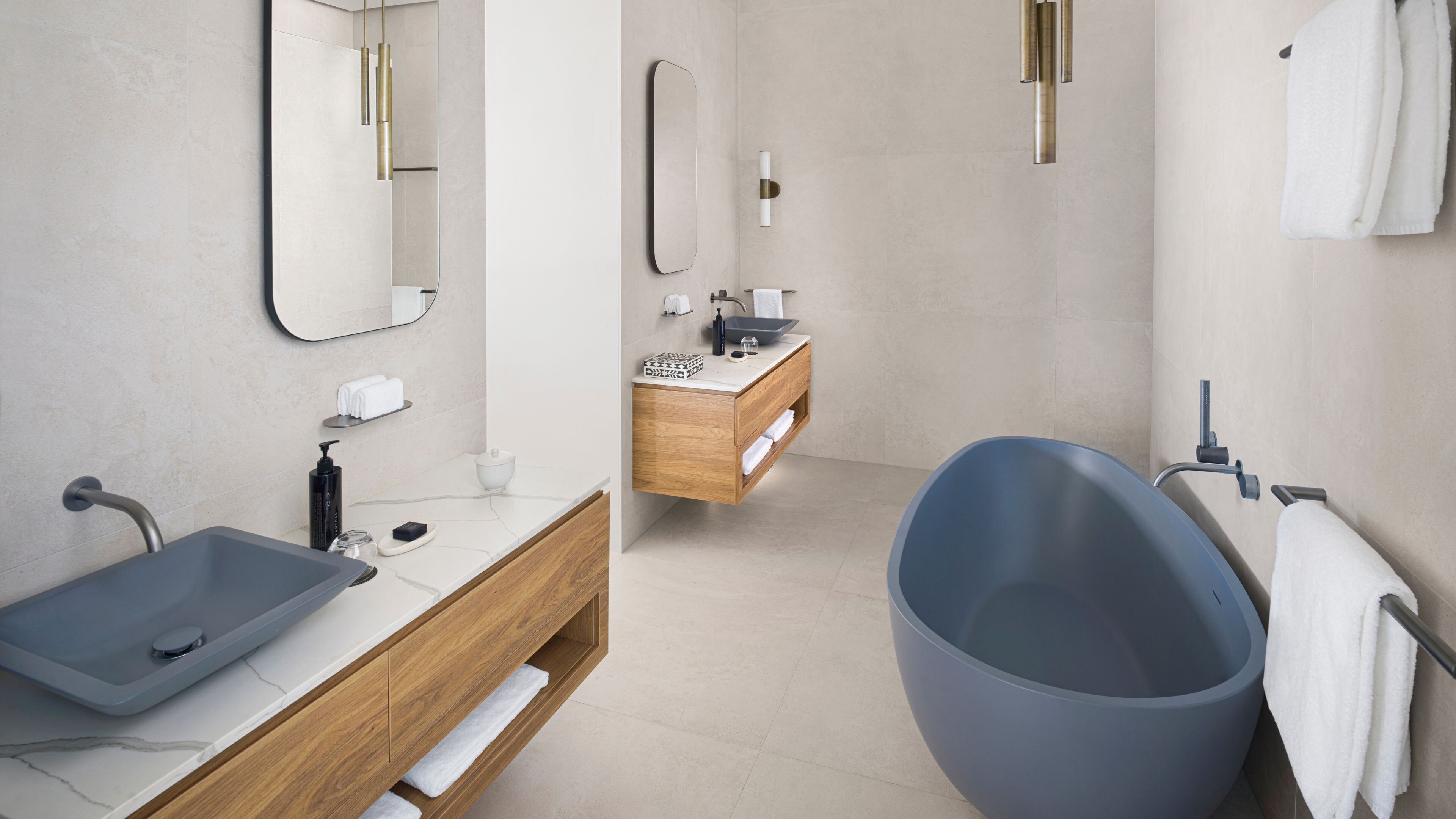 A modern bathroom with a large bathtub, a wooden vanity with a sink, and a mirror.