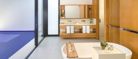 Un baño moderno con tocador de madera, un espejo grande y una bañera.