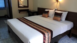 Een hotelkamer met een groot bed, een nachtkastje, een spiegel en een wandlamp.