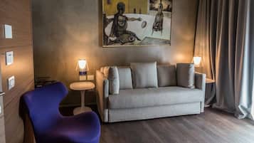 Un soggiorno moderno con un divano grigio, una poltrona blu e un quadro appeso al muro.