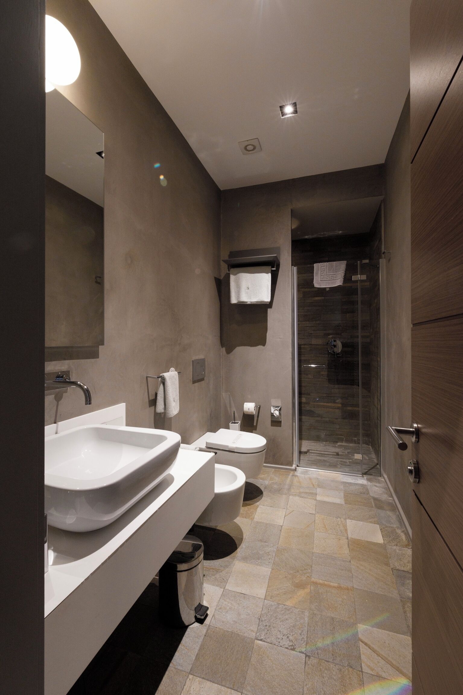 Un baño moderno con lavamanos grande, inodoro y ducha.